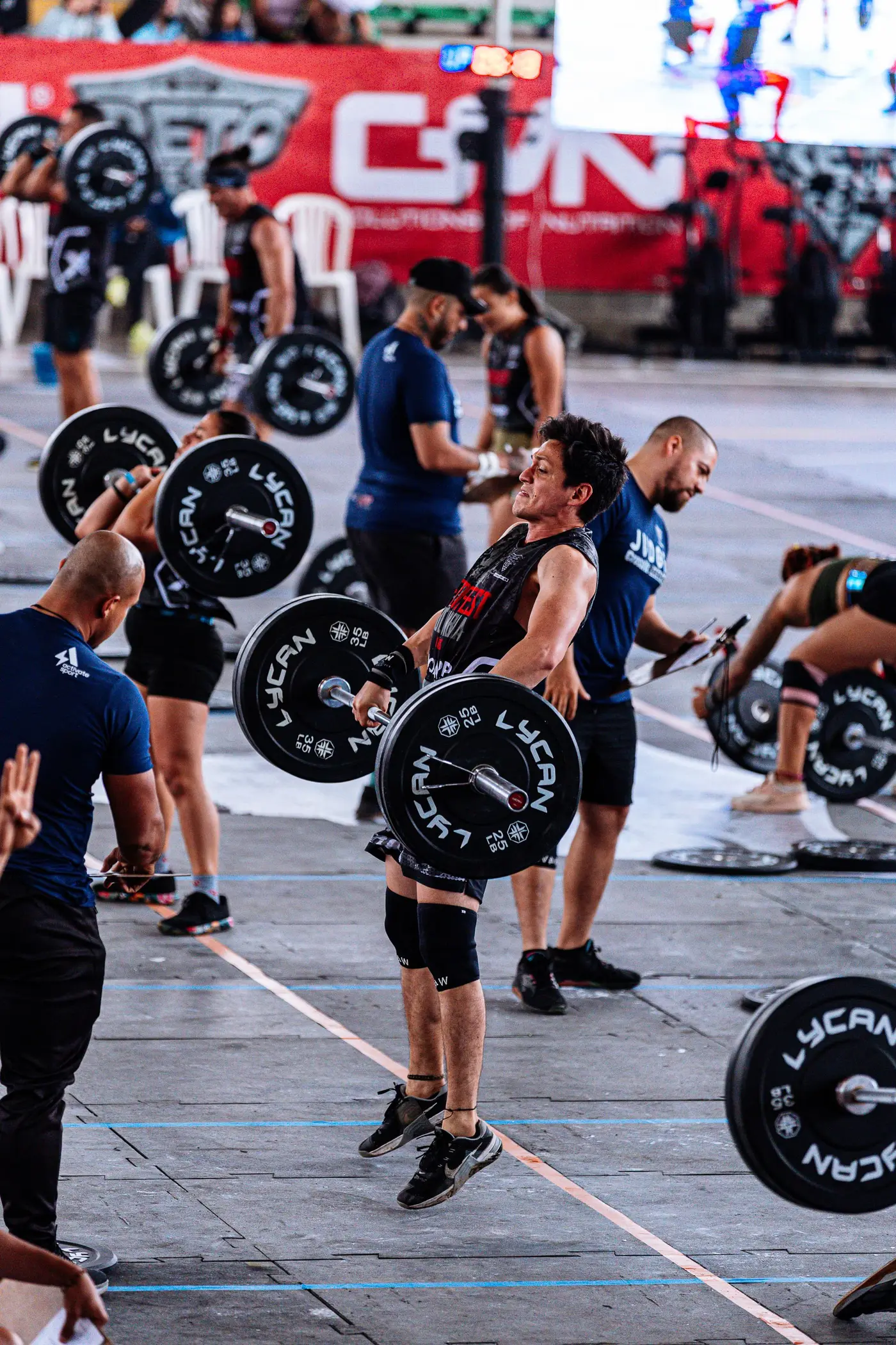 Grupo de atletas levantando barras a la vez en una competición